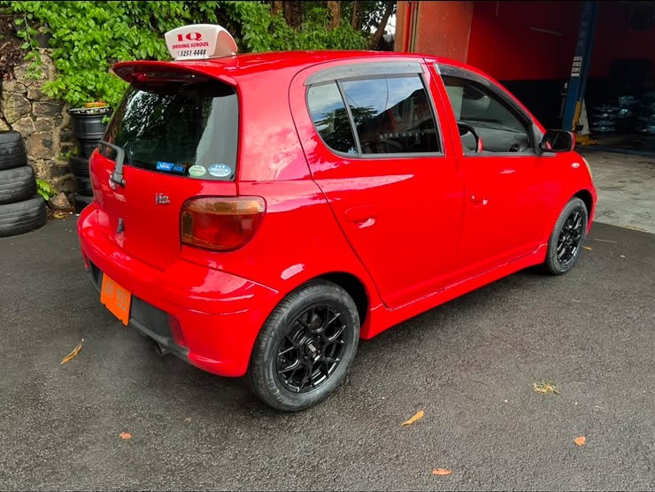 Rear-side view of a red IQ Driving School training car