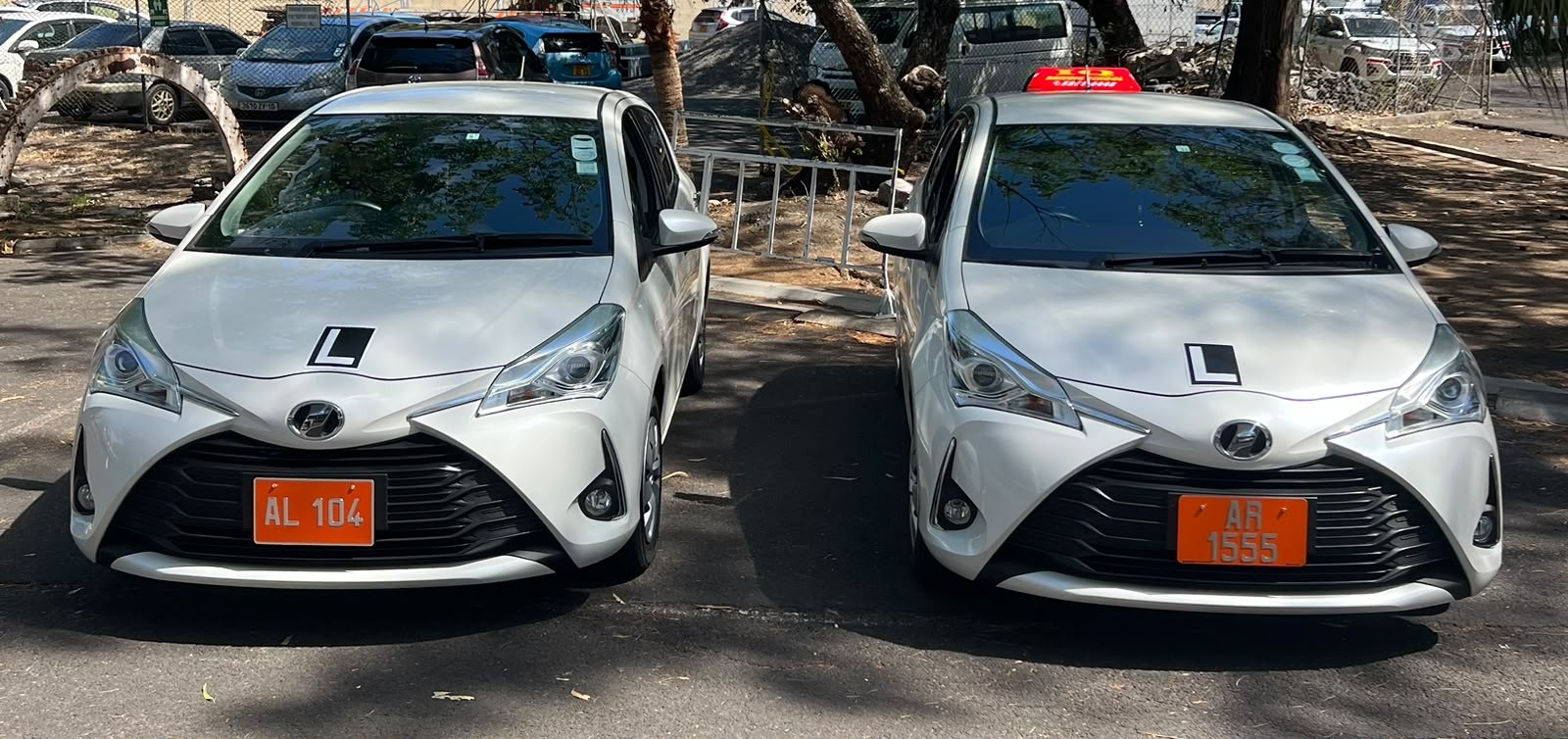 Two white IQ Driving School learner vehicles parked side by side
